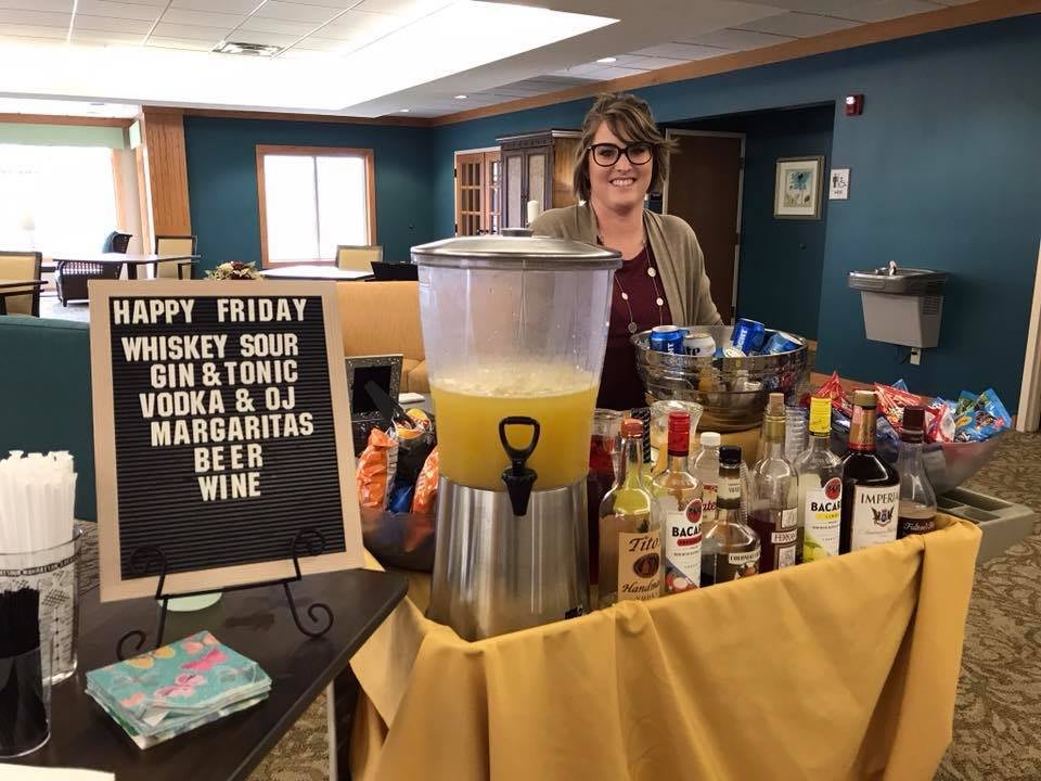 A cheerful bar setup with a variety of alcoholic beverages and a lemonade dispenser, ready for a festive happy hour event.