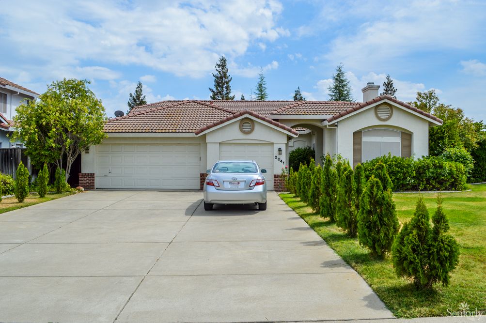 A suburban house with a driveway and car parked in front.