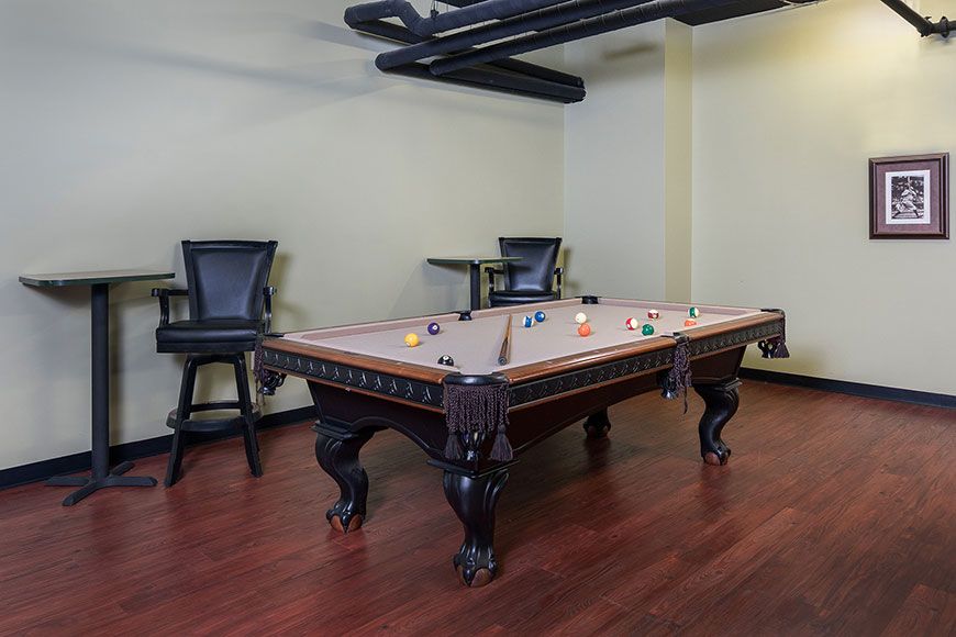 A stylish game room featuring a classic pool table with dark wooden elements.