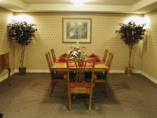 A cozy dining room setup featuring a wooden table surrounded by chairs, adorned with decorative plants and wall art.
