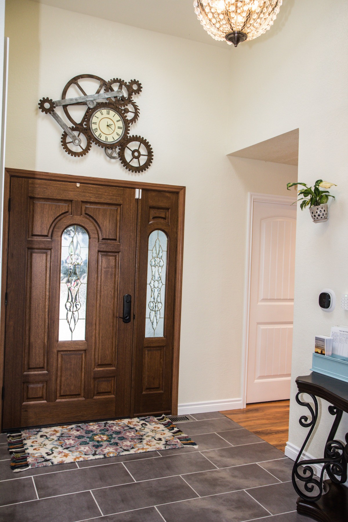 A stylish home entryway featuring a wooden door and decorative clock wall art.