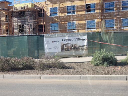 A construction site for 'Legacy Village' featuring scaffolding and a promotional banner.