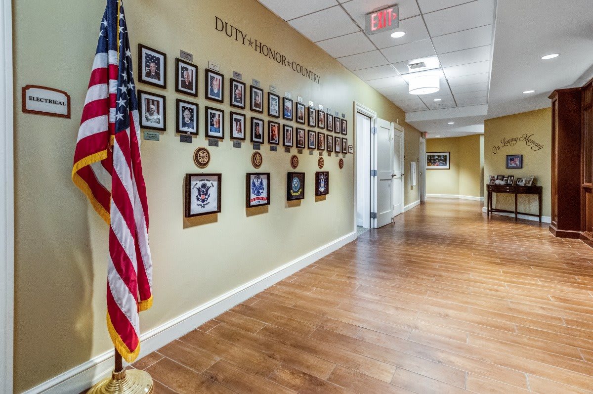 A hallway with framed photographs displayed on the wall and an American flag.