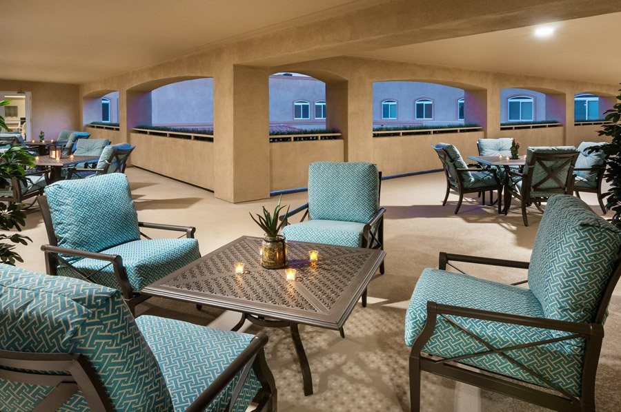 A cozy outdoor seating area with cushioned chairs and small tables, perfect for an evening gathering.