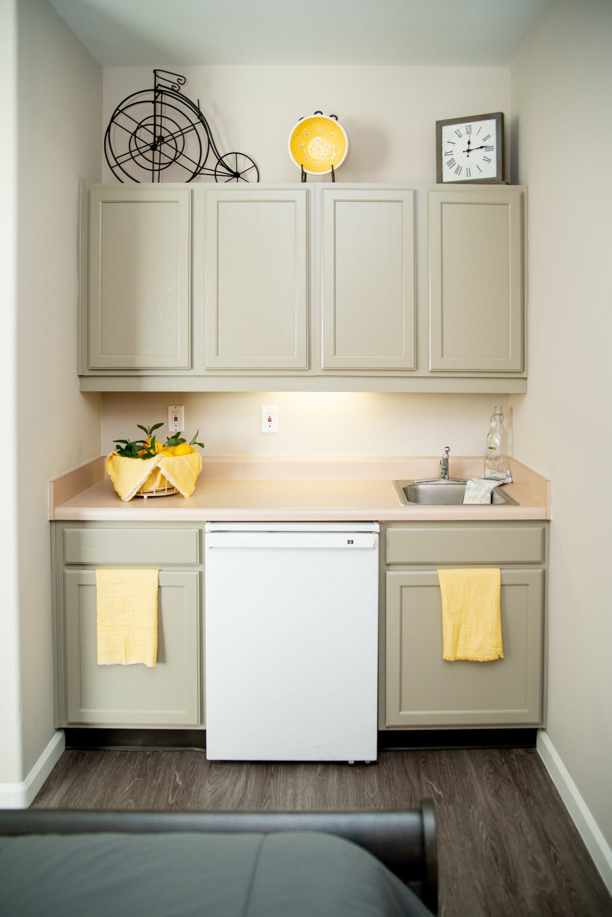 A minimalist kitchen setup featuring light-colored cabinets, a small sink area, and yellow accents.