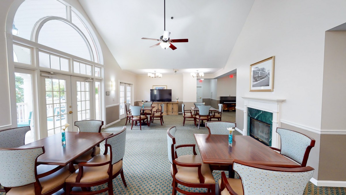A cozy dining area with tables, chairs, a television, and a fireplace.