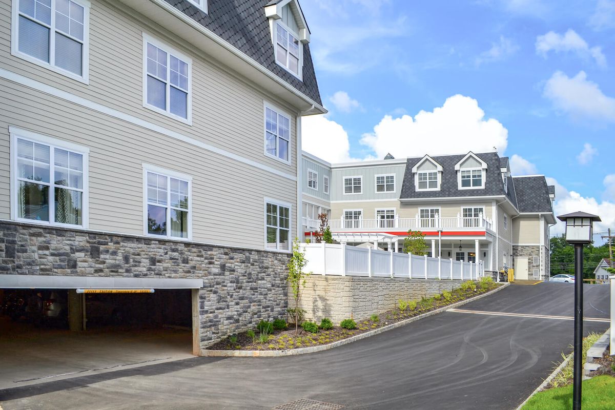 Modern apartment buildings with a stone entrance and a driveway on a clear day.
