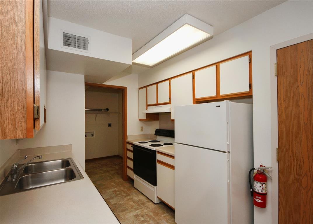 A compact apartment kitchen with essential appliances and white cabinets.