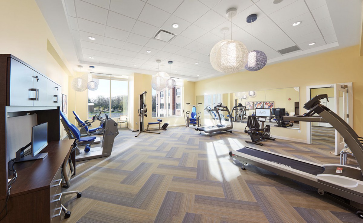 A well-lit gym with various exercise equipment and treadmills.