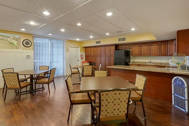 A modern kitchen and dining area featuring wooden flooring, equipped with tables and chairs.