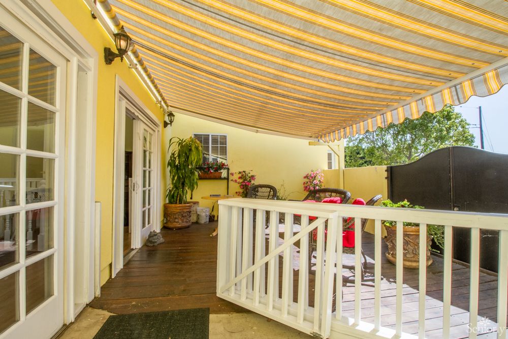 A cozy patio with an awning, featuring outdoor seating and vibrant yellow walls.