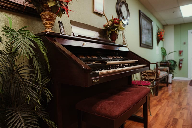A vintage organ with a bench set in a cozy room filled with decorative items.