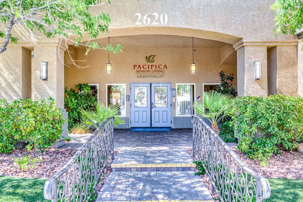 Entrance to a building with a landscaped walkway and greenery.