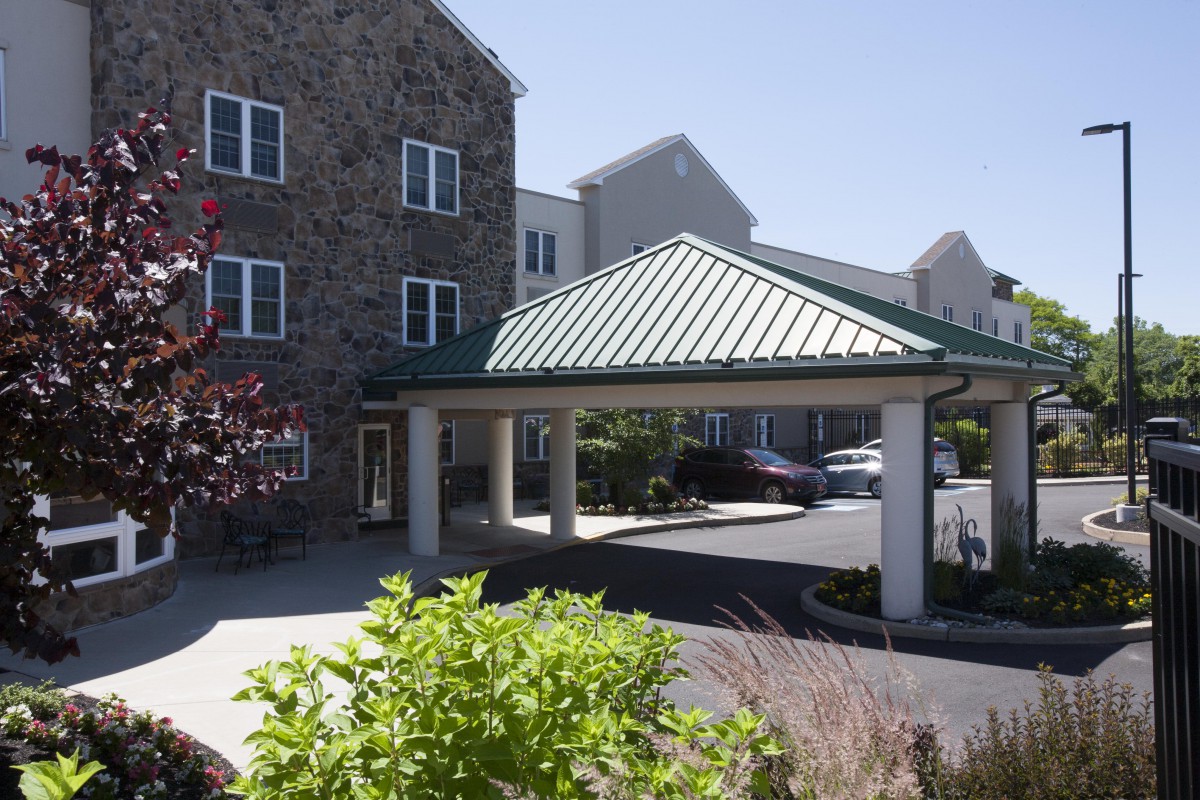 A building with a covered entrance and landscaped surroundings.