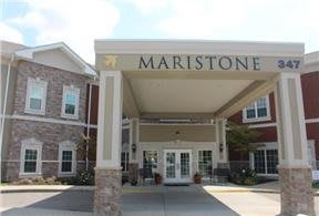 The entrance of the Maristone building, featuring a covered driveway and brick architecture.