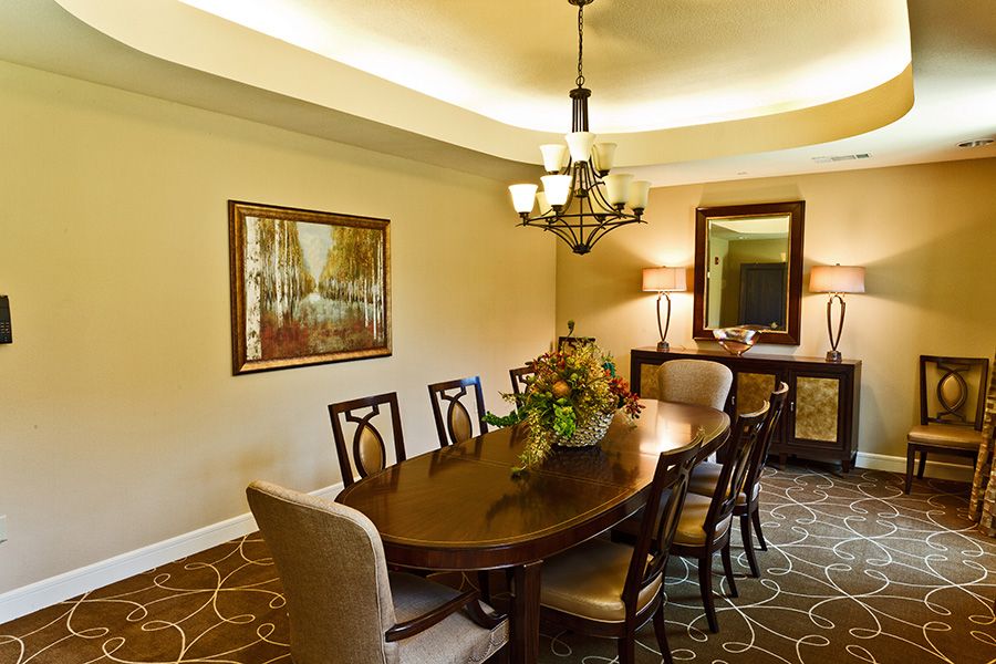 A well-decorated dining room featuring a wooden table with chairs, a chandelier, and a framed painting on the wall.
