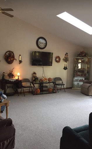 A cozy living room featuring a wall-mounted television, decorative wall hangings, and comfortable seating.