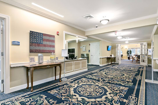 A well-decorated lobby area featuring a large carpet, a table with decorative items, and an American flag artwork on the wall.