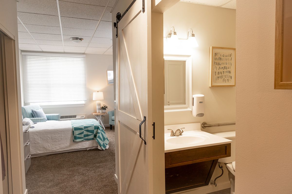 A modern bedroom with an attached bathroom, separated by a stylish barn door.
