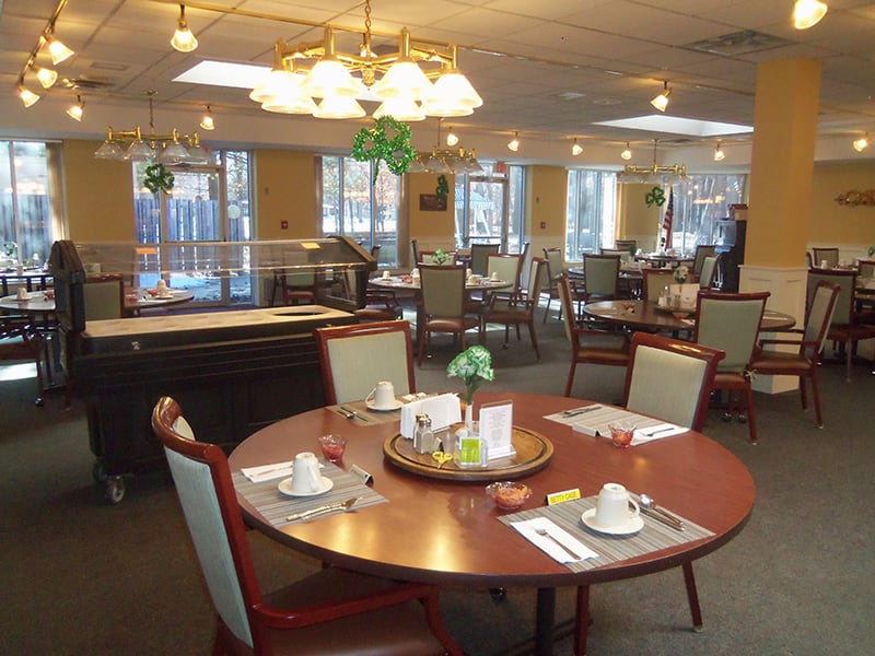 A well-lit dining area with neatly set tables and chairs, featuring elegant decor.