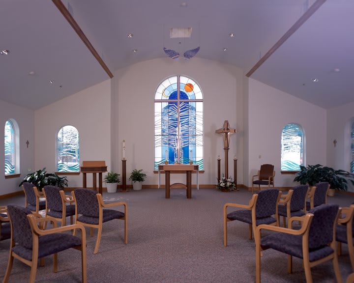 A serene chapel interior with an altar and stained glass windows.