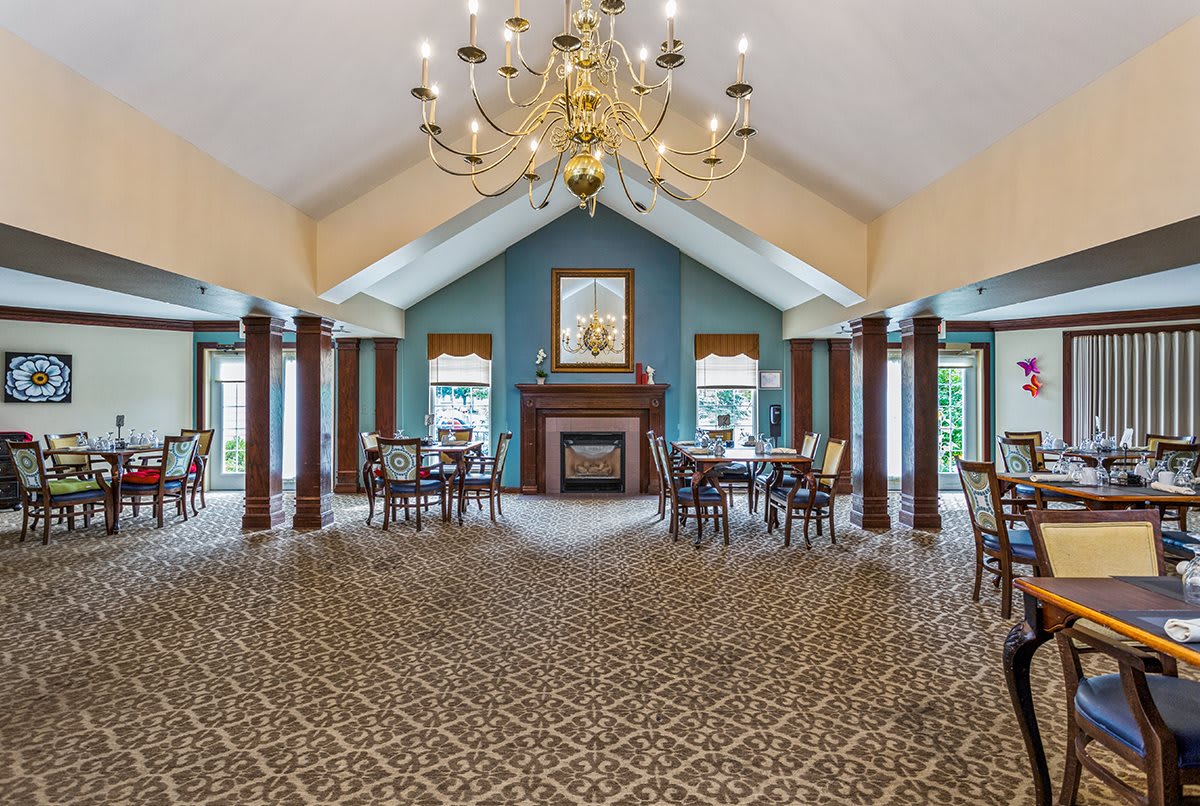 A spacious dining area with elegant decor, featuring a grand chandelier, a fireplace, and vaulted ceilings.