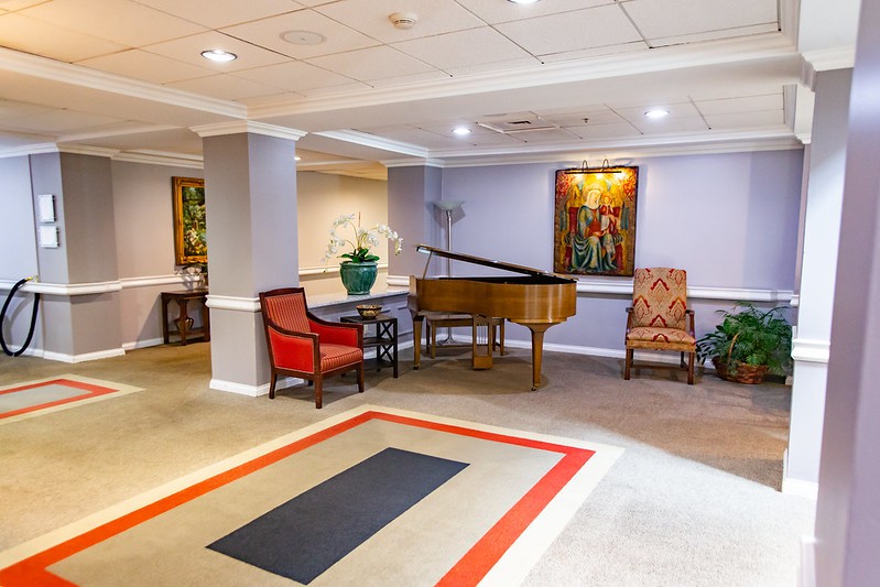 A well-decorated lobby featuring a grand piano, artwork, and comfortable seating.