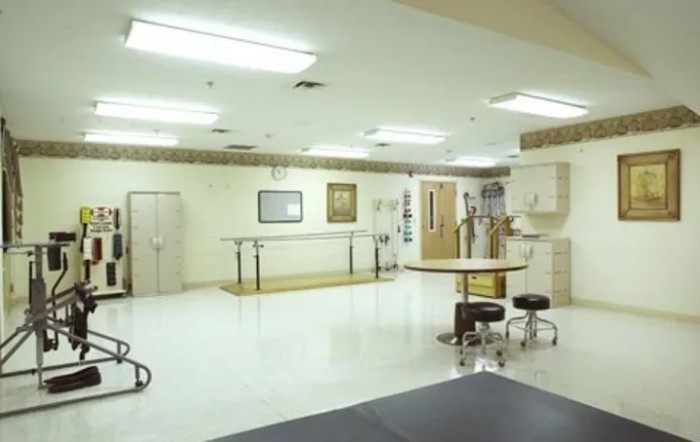 A spacious physical therapy room equipped with medical equipment for rehabilitation and treatment.