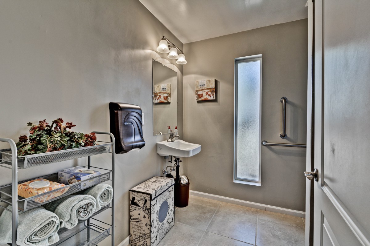A well-lit bathroom with modern decor, featuring a sink, mirror, and tiled floor.