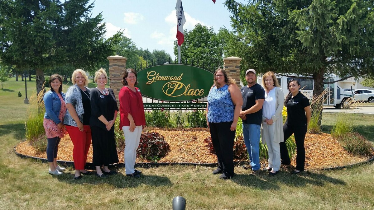 A group of people standing in front of a sign that reads 'Greenwood Place'.
