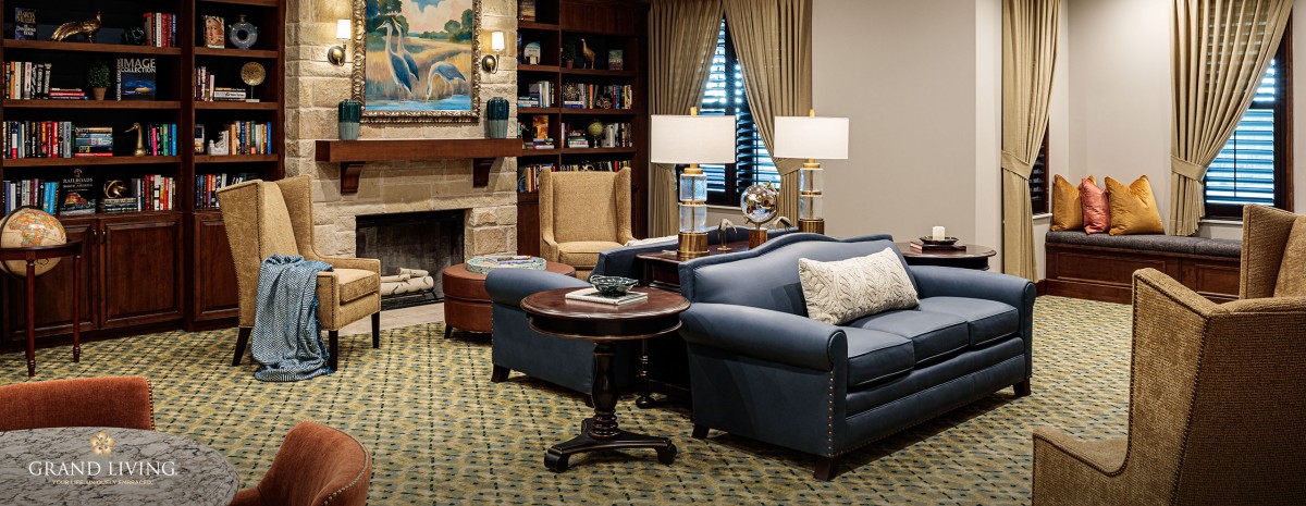 A cozy living room with a sofa, armchair, and fireplace.
