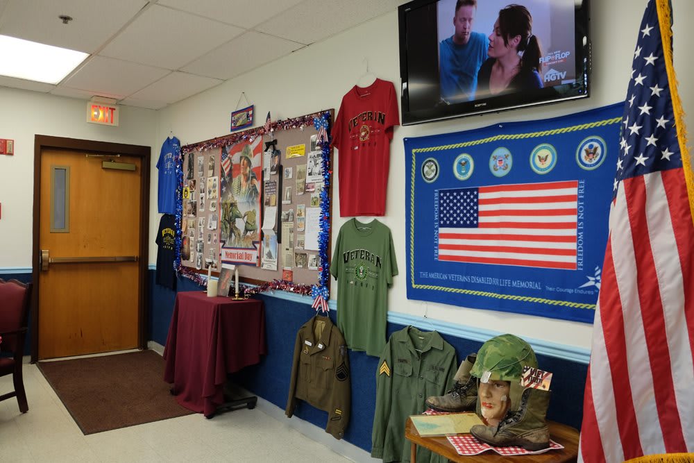 A hallway display featuring military memorabilia, including uniforms, helmets, and an American flag, paying tribute to veterans.