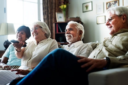 A group of seniors sitting indoors, enjoying each other's company and sharing a laugh.