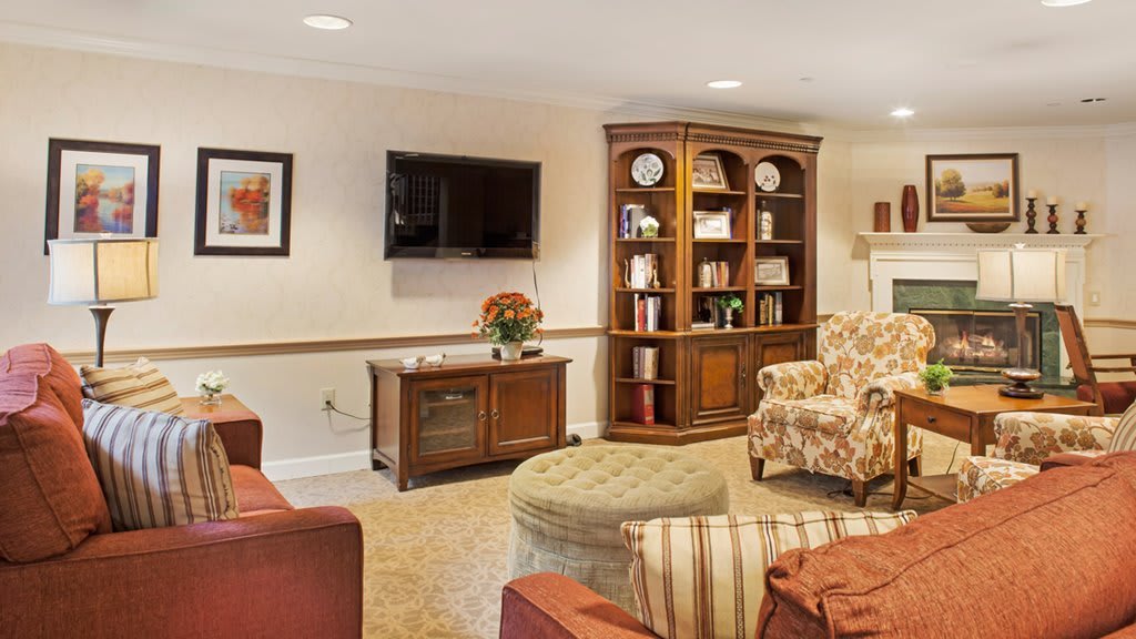 A cozy living room with a bookshelf, armchairs, and a television.