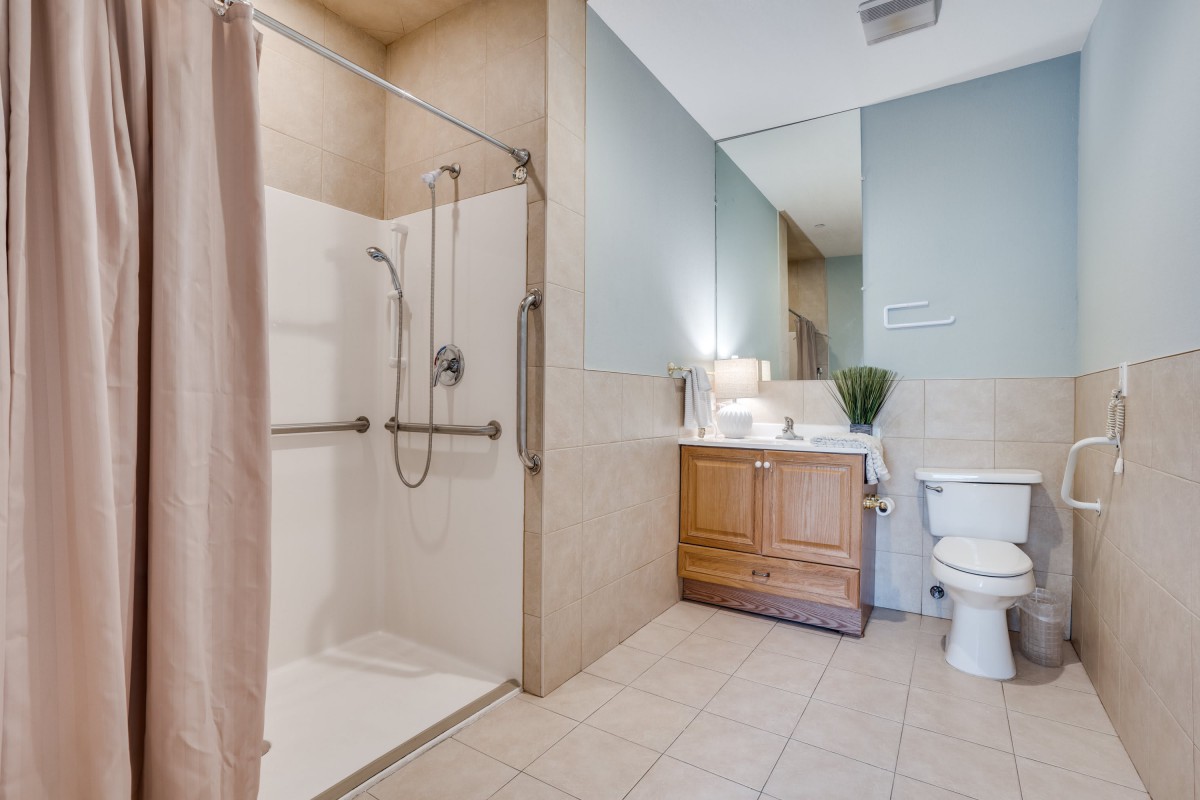 A modern bathroom featuring a walk-in shower, vanity with mirror, and toilet.