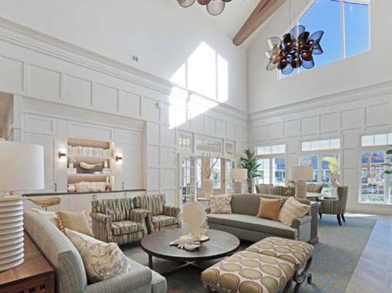 A spacious and well-lit living room featuring modern furniture and high ceilings.