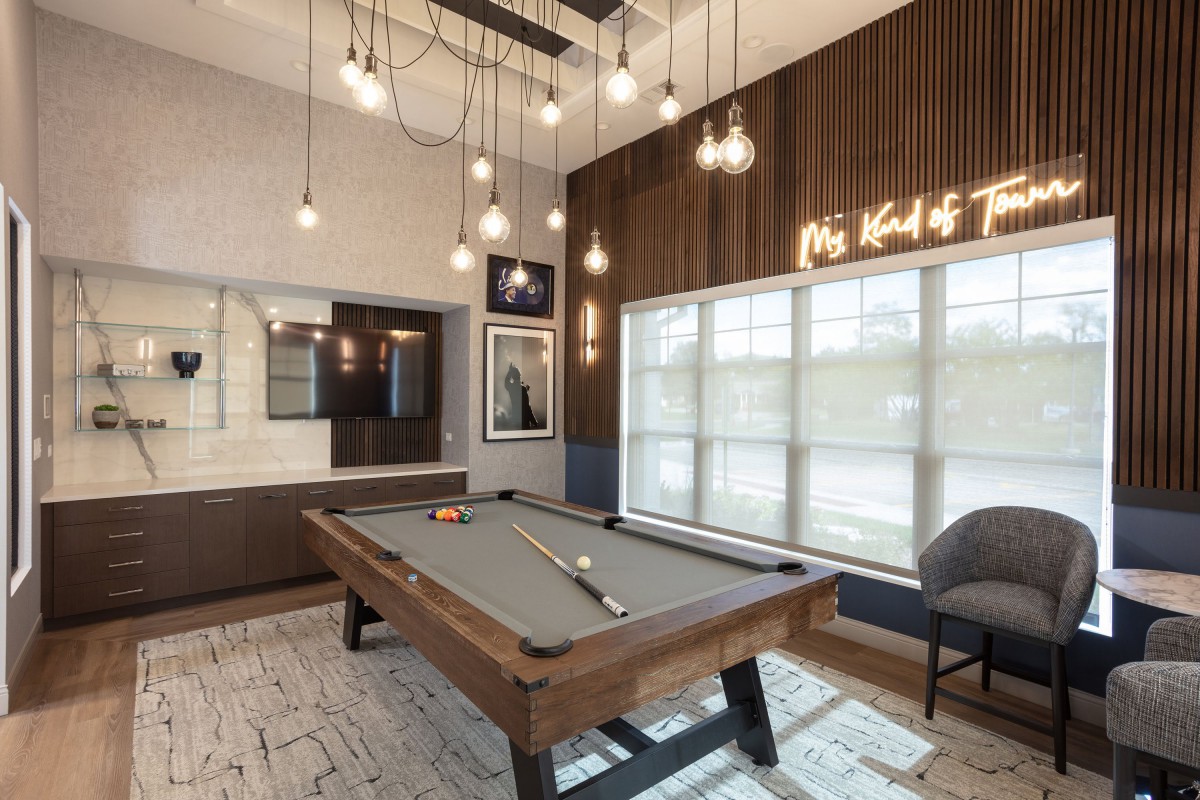 A modern game room featuring a pool table with stylish pendant lighting and contemporary decor.