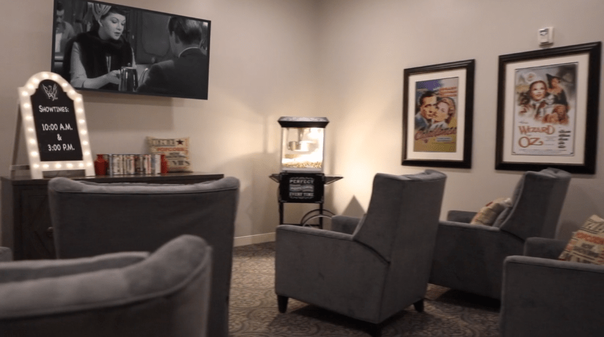 A cozy home theater setup with comfortable chairs, a popcorn machine, and artwork on the walls.