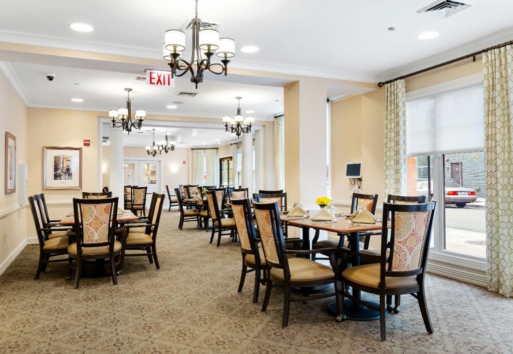A spacious dining room with elegant furniture and chandeliers.