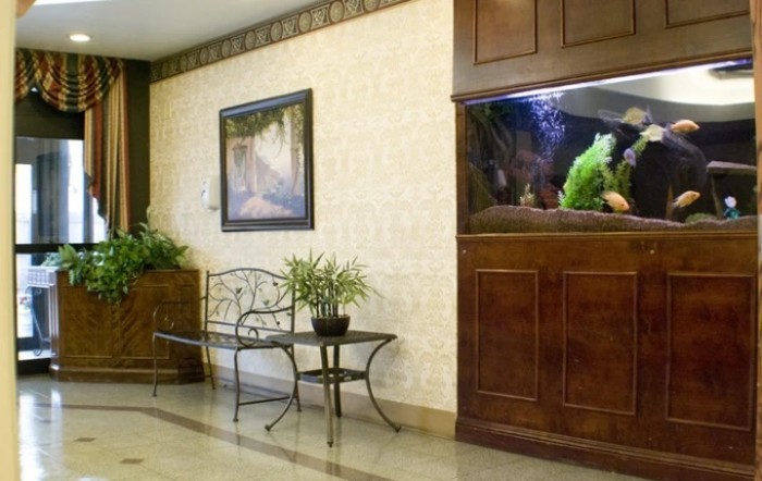 A cozy interior space featuring a built-in aquarium, a decorative bench with potted plants, and framed artwork on the wall.