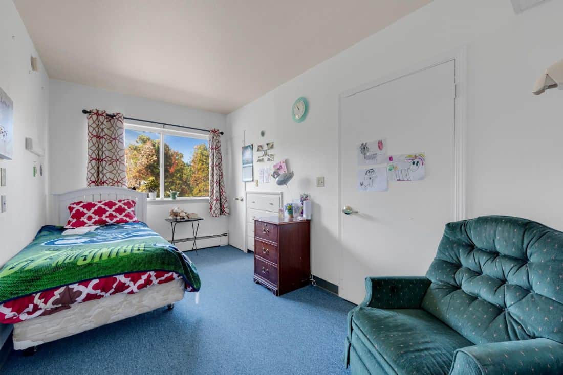 A cozy bedroom with a large window and comfortable furniture.