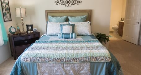 A neatly made bed featuring patterned quilts and decorative pillows in a cozy bedroom.