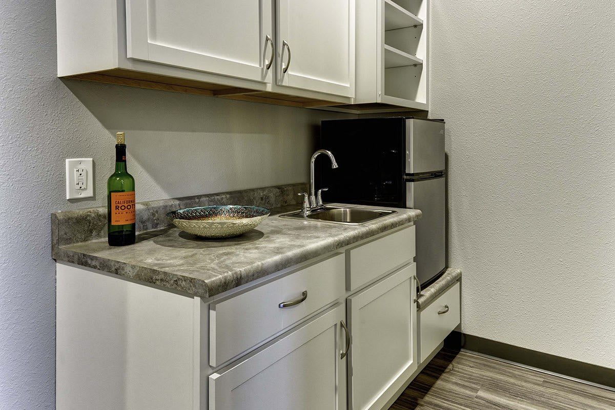 A small kitchen area featuring cabinets, a countertop with a sink, and a refrigerator.
