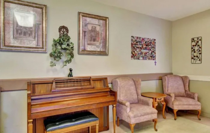 A cozy indoor seating area with a piano and framed artwork on the walls.