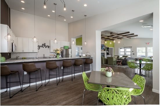 A modern kitchen with bar seating and vibrant green chairs in a spacious open area.