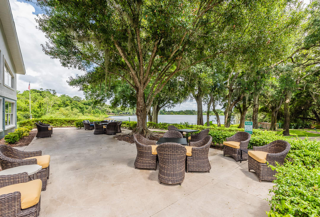 A tranquil outdoor patio with wicker furniture surrounded by lush trees.