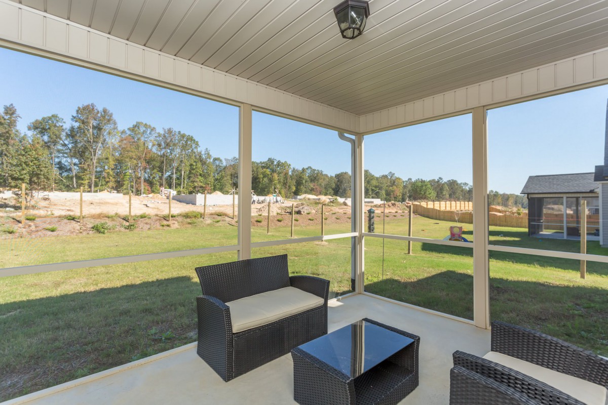 A cozy patio with modern outdoor furniture overlooking a spacious backyard.