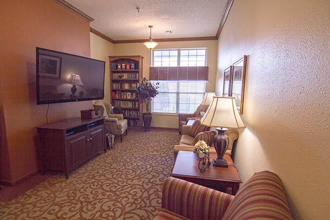 A cozy living room with a television, bookshelf, and comfortable seating.