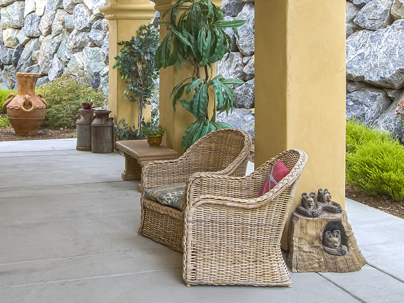 A cozy outdoor patio area with wicker chairs and plants.