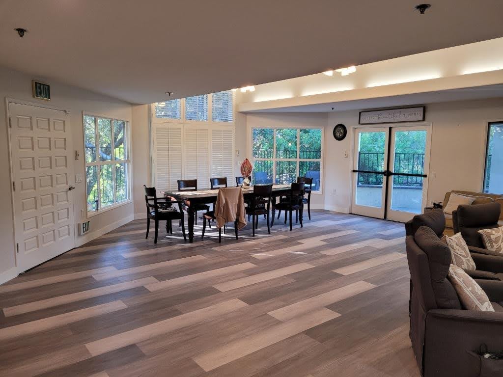 A spacious dining area with a wood floor and large windows offering natural light.